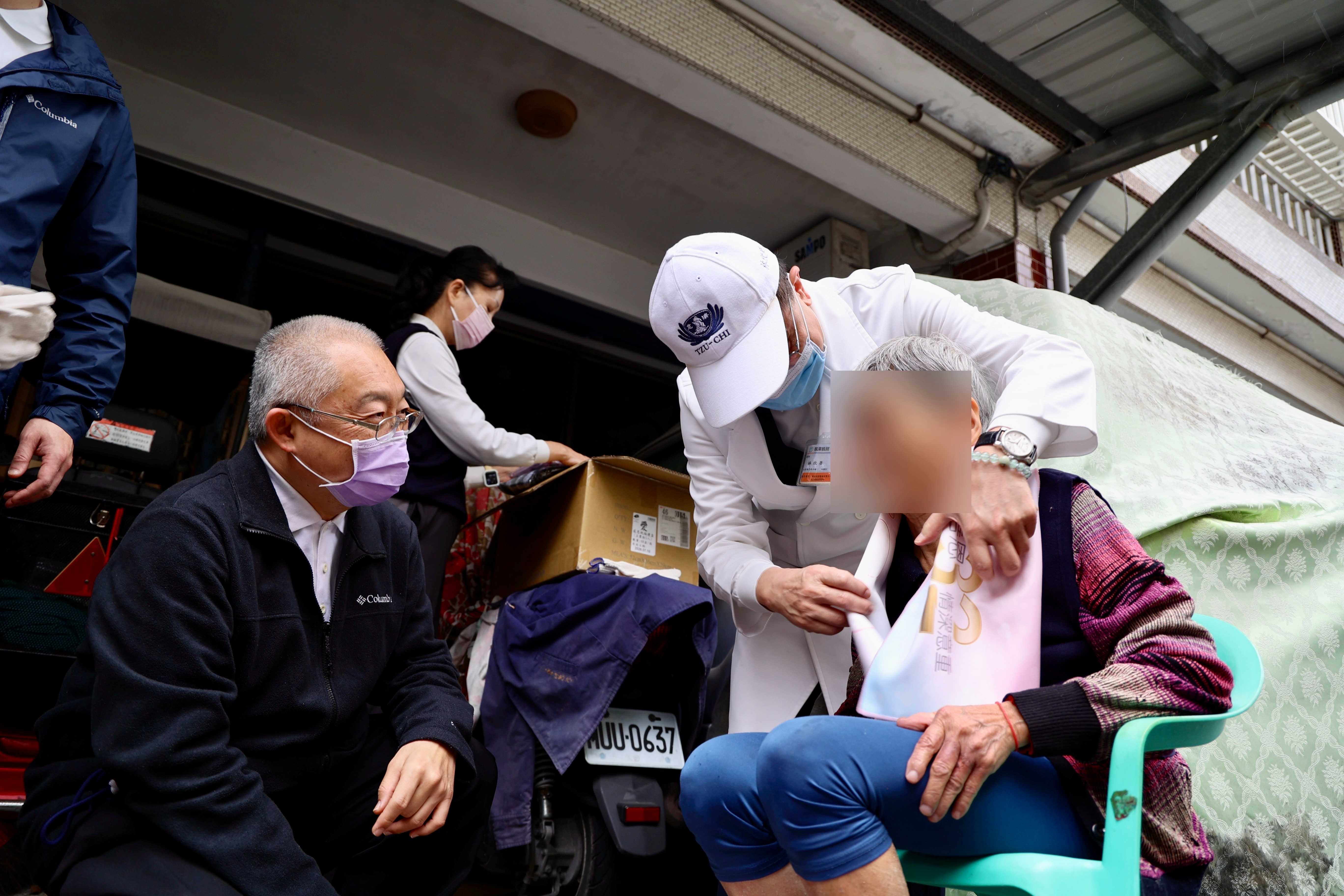 花蓮慈院林欣榮院長與特殊需求者牙科主任李彞邦為阿嬤送上背心新衣與圍巾，祝福溫暖過新年