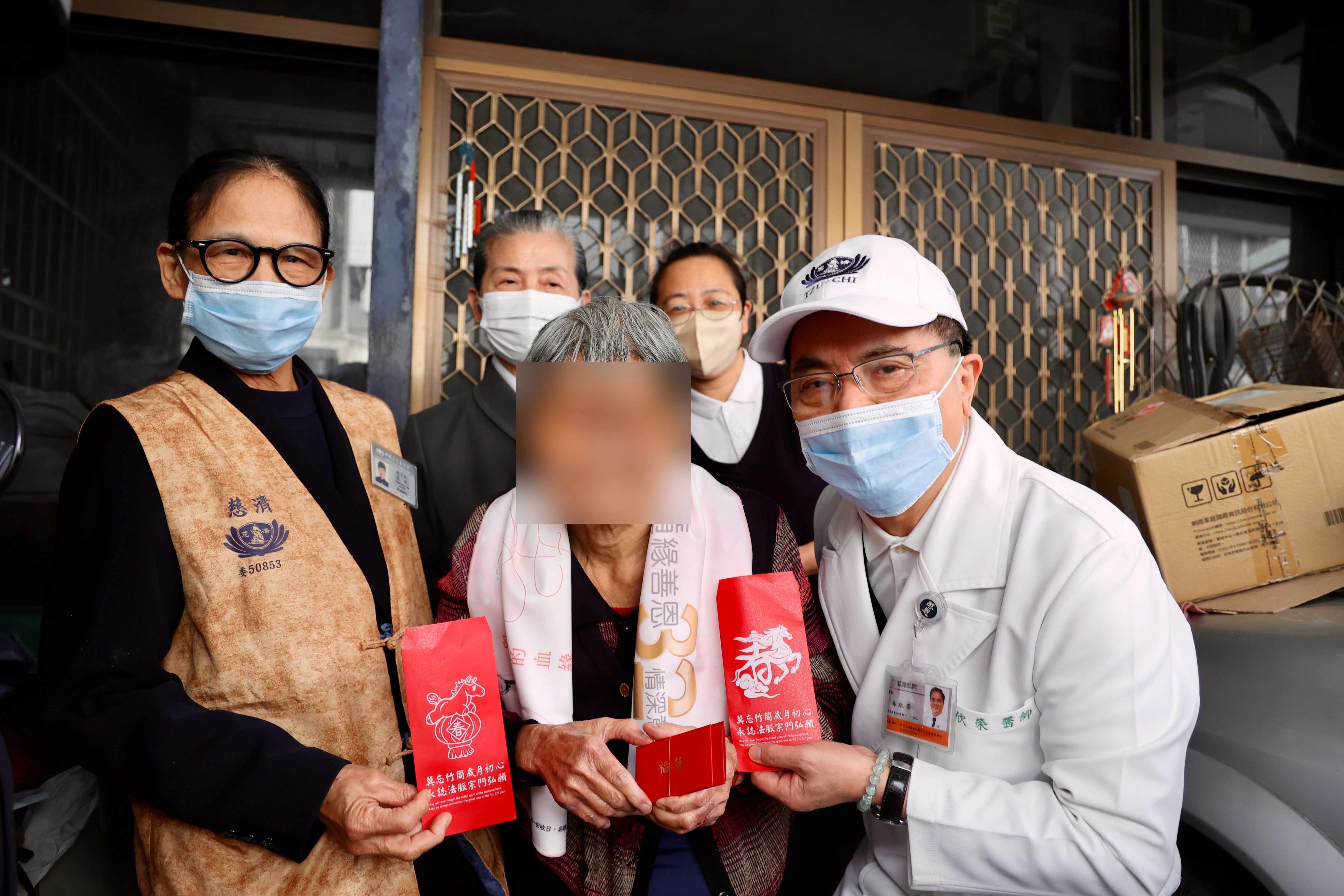 花蓮慈院林欣榮院長（白袍）與顏靜曦師姊（後排灰衣）為阿公阿嬤送上證嚴上人的祝福紅包，以及新年物資。