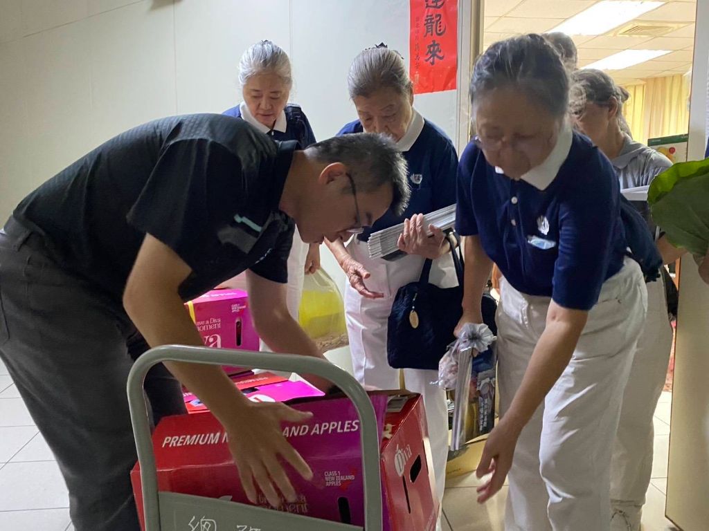 在大安分局同仁詹世銘（左一）的陪同下，用推車將福緣珍粥等物資用「走動式關懷」的方式，將慈濟人的祝福逐層分送。