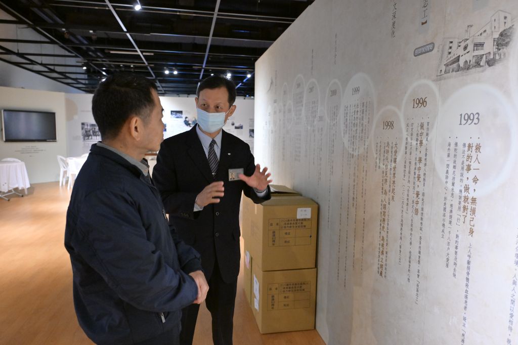 志工駱怡君(右)引領許先生到展覽區，了解慈濟五毛錢的力量發揮到全世界。希望每一個人從新年開始，可以發揮良能。