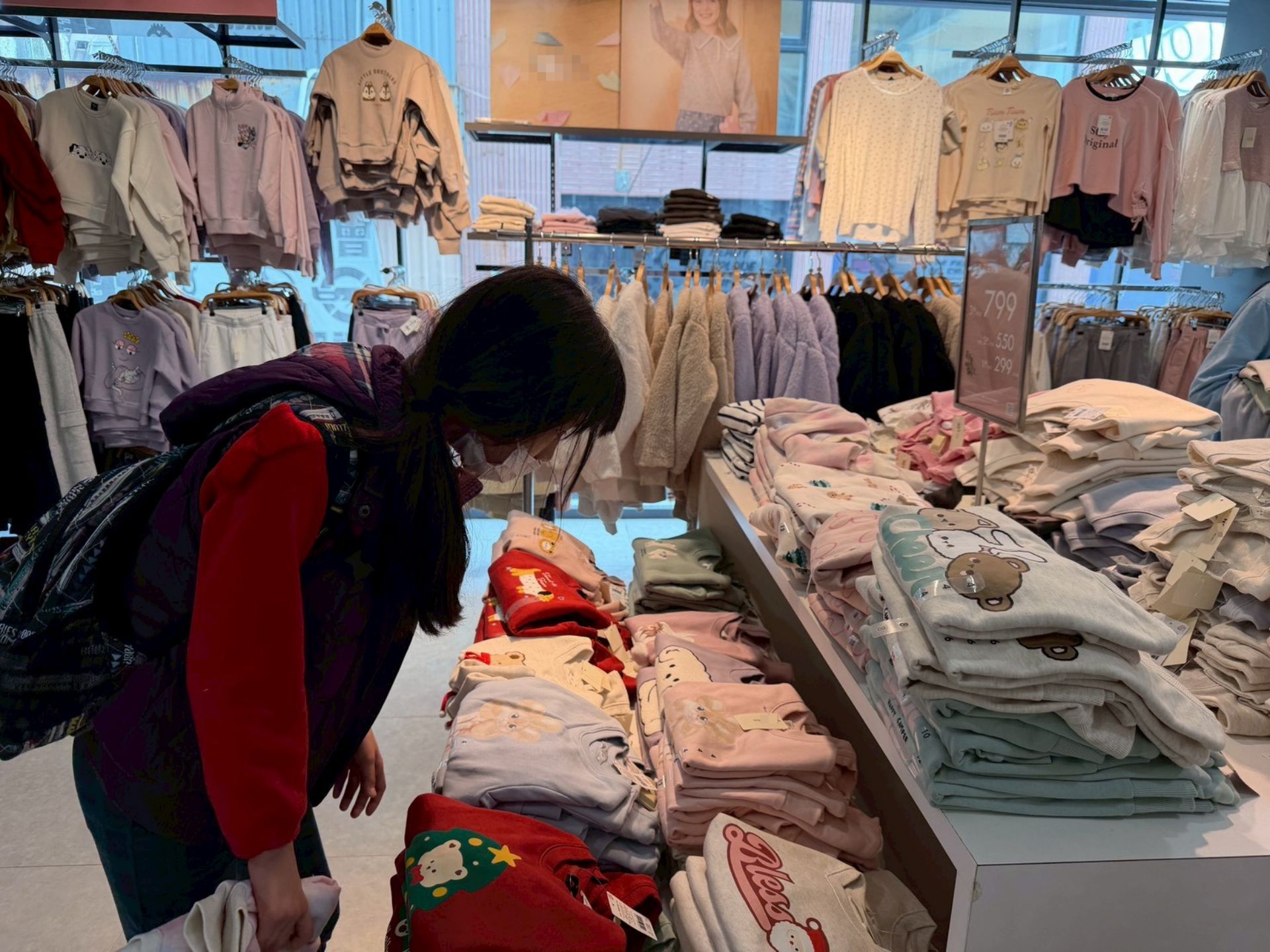 在社工陪伴下,姊妹走進服飾店挑選衣物。小欣站在衣架前反覆端詳,在少有自主選擇的經驗中,練習為自己做決定。(台灣世界展望會提供)