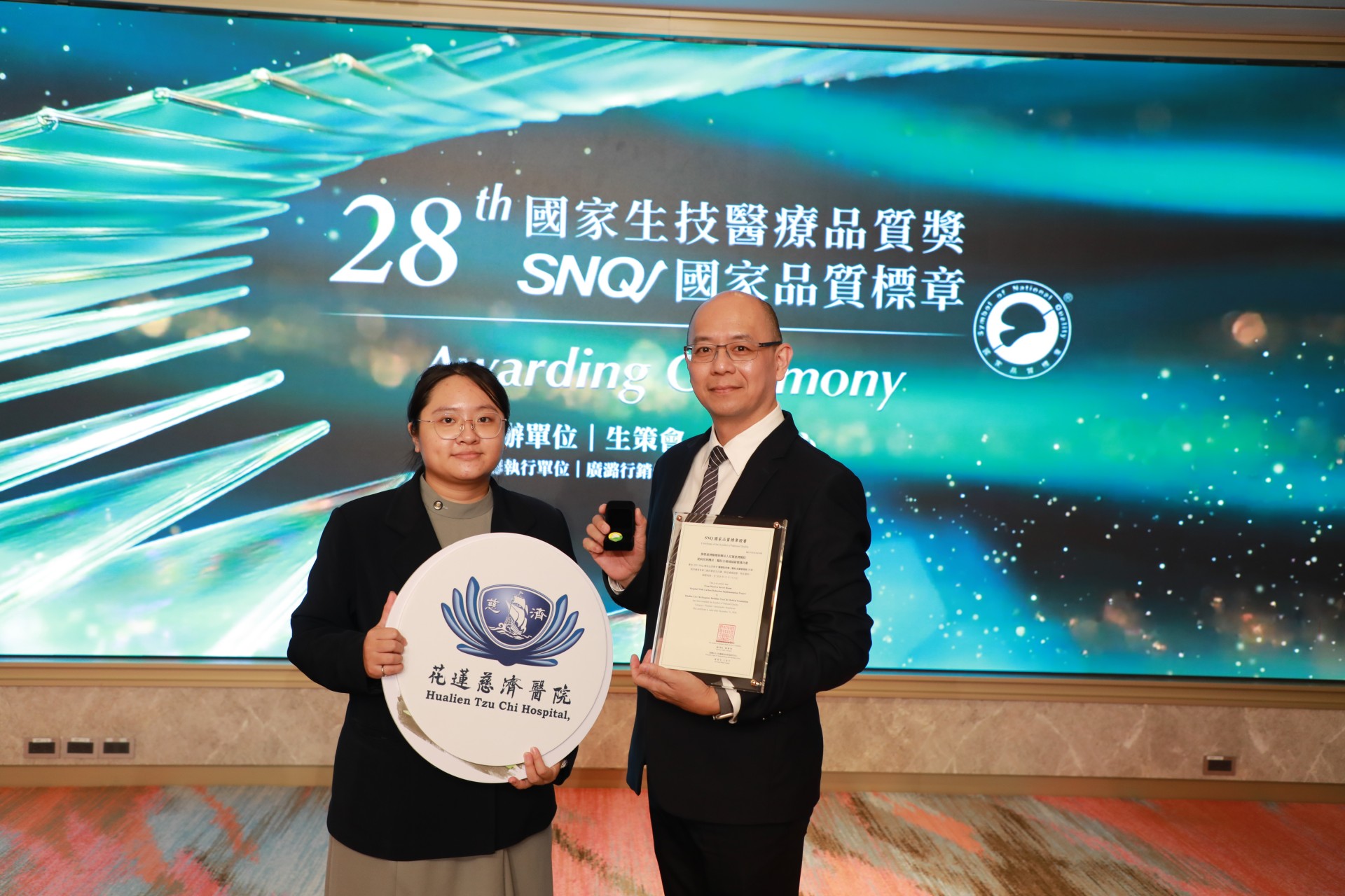 心臟內科「以團隊為基、以病人為本：心臟衰竭整合照護與居家支持創新實踐」獲得SNQ國家品質標章。由張懷仁醫師(左)與個案管理師蔡瑩琦代表受獎。
