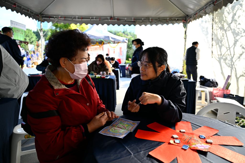 青年志工張簡棫薽(右)在「超人上場 翻好年」這一站，與會眾互動。