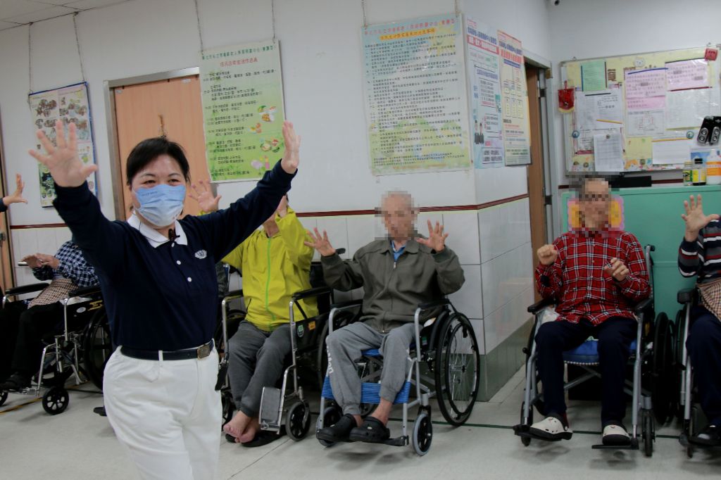 志工黃麗鳳（左一）帶領長者們活動筋骨，一邊說、一邊示範，長者和志工們一起動起來，熱絡的氣氛，在寒冷的冬天，增添暖意。
