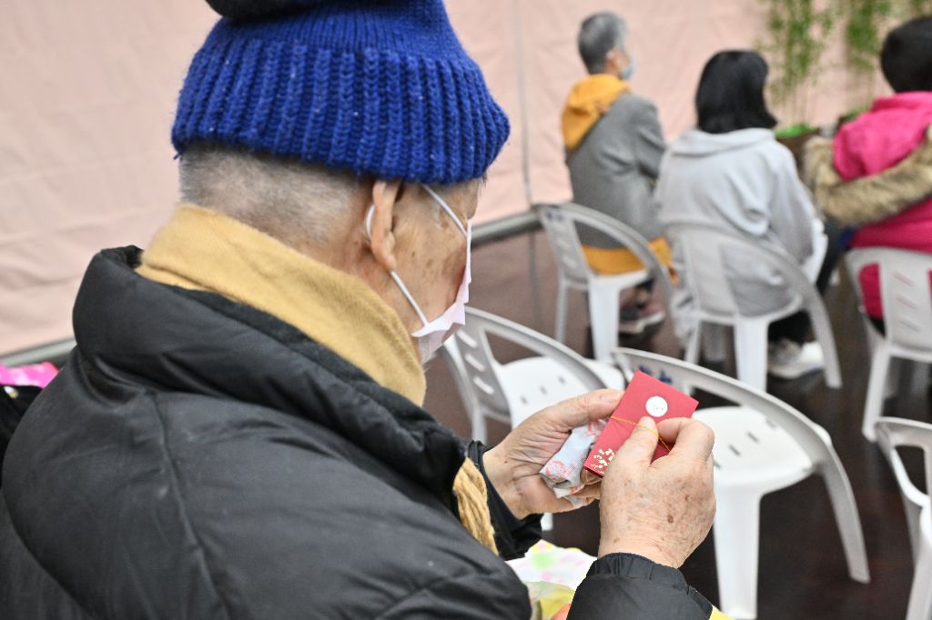 靜思精舍常住師父走到座位區，為養護中心的長者祝福，收到師父結緣的福慧紅包，長者珍惜的將它握在手中仔細端詳。