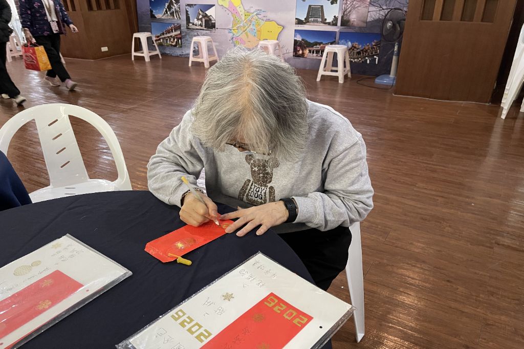 六十七歲徐碧娥是樂齡成長班學員，十分喜愛禪繞畫，今年首次設置禪繞畫攤位，她特地為自己繪製一個專屬於2026年的禪繞畫紅包，對照樣本一筆一畫，格外專注投入。