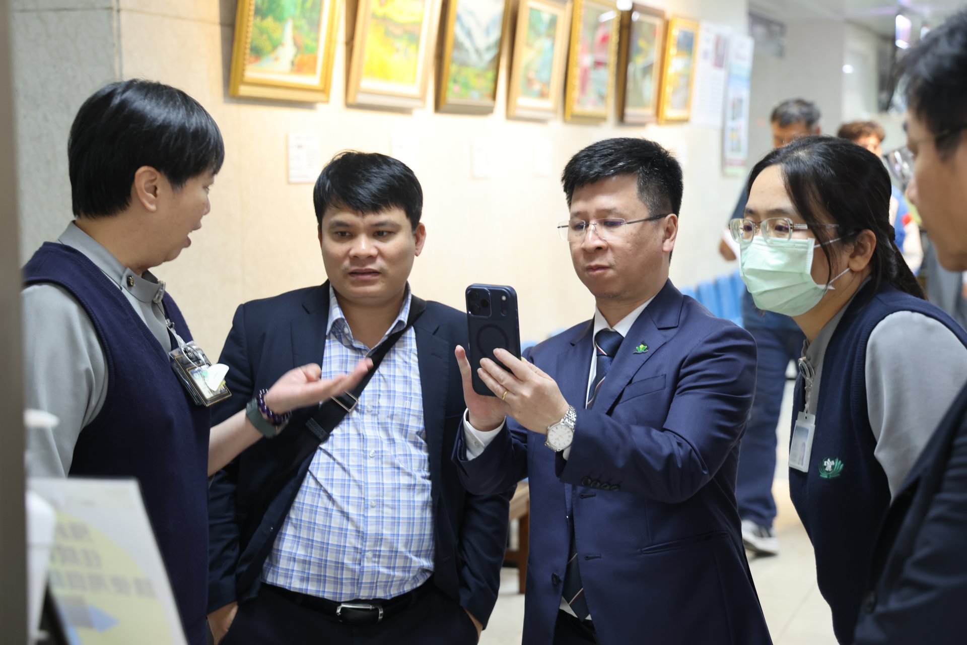 花蓮慈院醫事室張菁育主任(左)介紹入出院自動系統，來自越南的高越松副院長認真的以手機記錄。