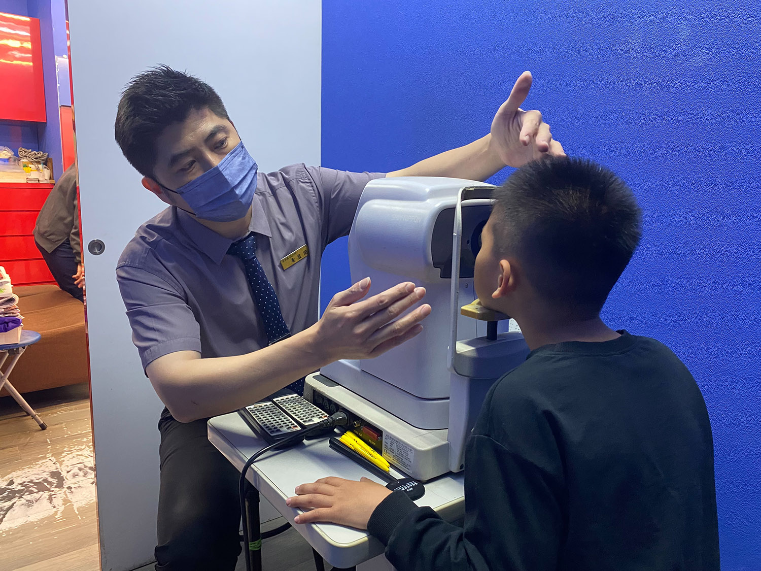 1元眼鏡店長在驗光室仔細測量視力、協助挑選鏡框與鏡片，並提供專業建議，確保眼鏡最適合孩子佩戴。(台灣世界展望會提供）