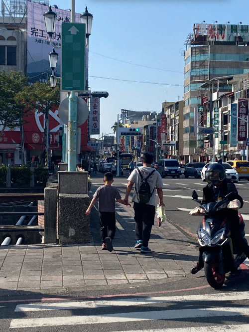 展望會社工正昌(右)特地開近一小時車程，接送小城到眼鏡行，結束後牽著他小小的手過馬路，一路陪伴，確保孩子順利完成驗光與鏡片挑選。(台灣世界展望會提供）