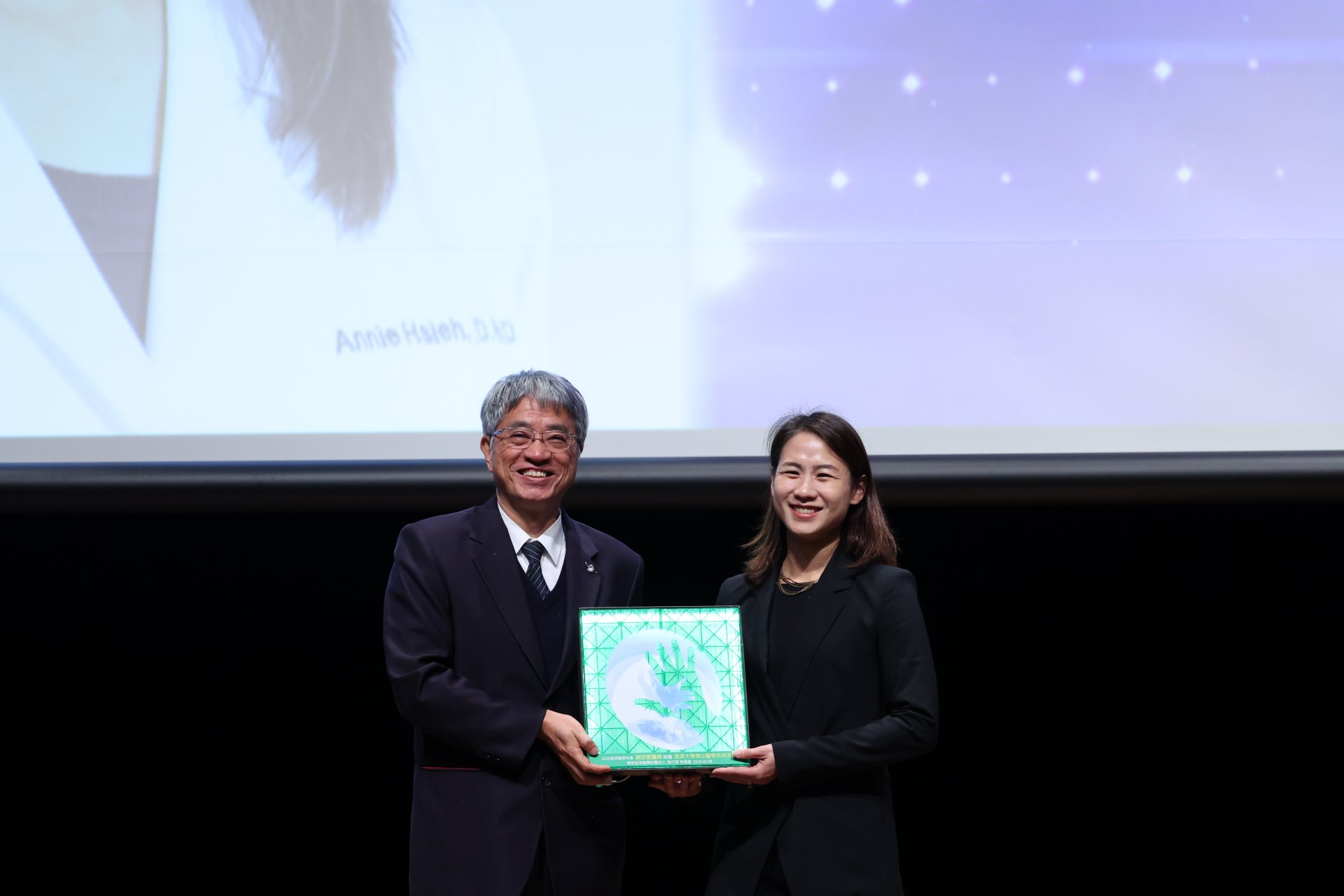 慈大傑出校友謝安妮(右)，現為美國麻省總醫院神經腫瘤專科醫師，從副校長陳宗鷹手中接獲「傑出醫學系校友獎」，她感恩慈大教會她真正的慈悲。