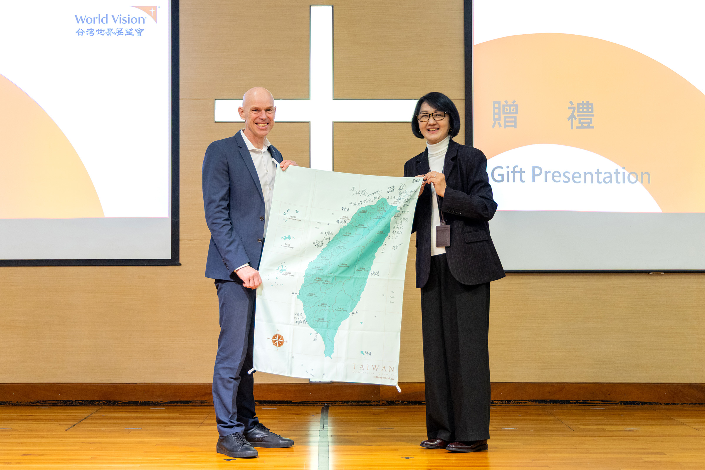 世界展望會國際總裁安德魯‧莫利(左)訪台，台灣世界展望會會長李紹齡(右)致贈工作團隊簽名錦旗歡迎。(台灣世界展望會提供)