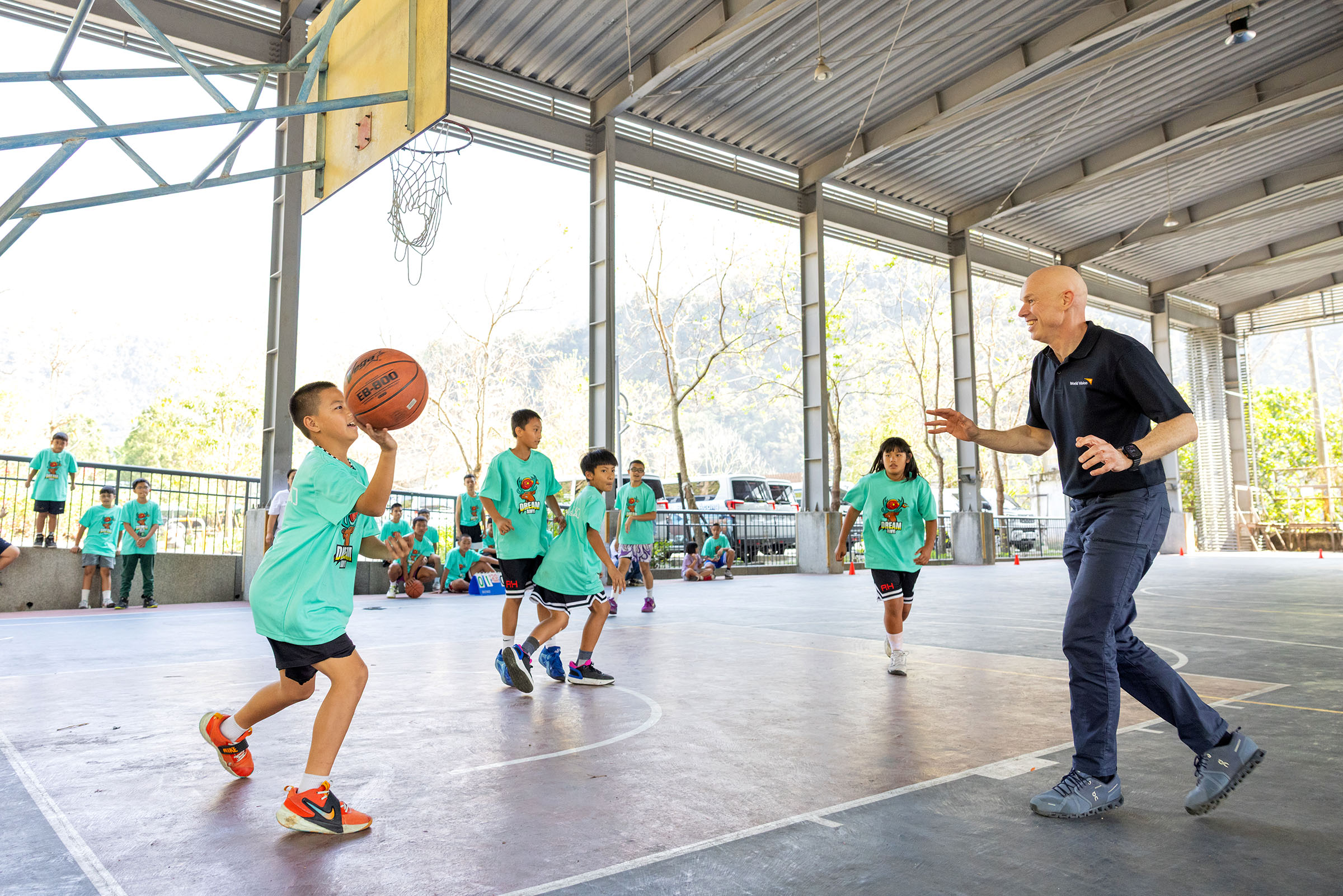 安德魯‧莫利在地利村風雨球場，和信義夢幻隊的孩子報隊打籃球。(台灣世界展望會提供)
