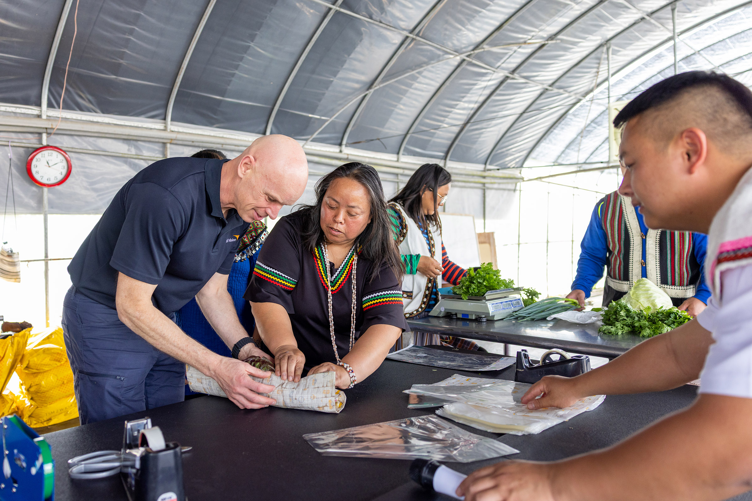 在部落媽媽引導下，安德魯‧莫利學習包裝新鮮蔬菜的技巧。(台灣世界展望會提供)