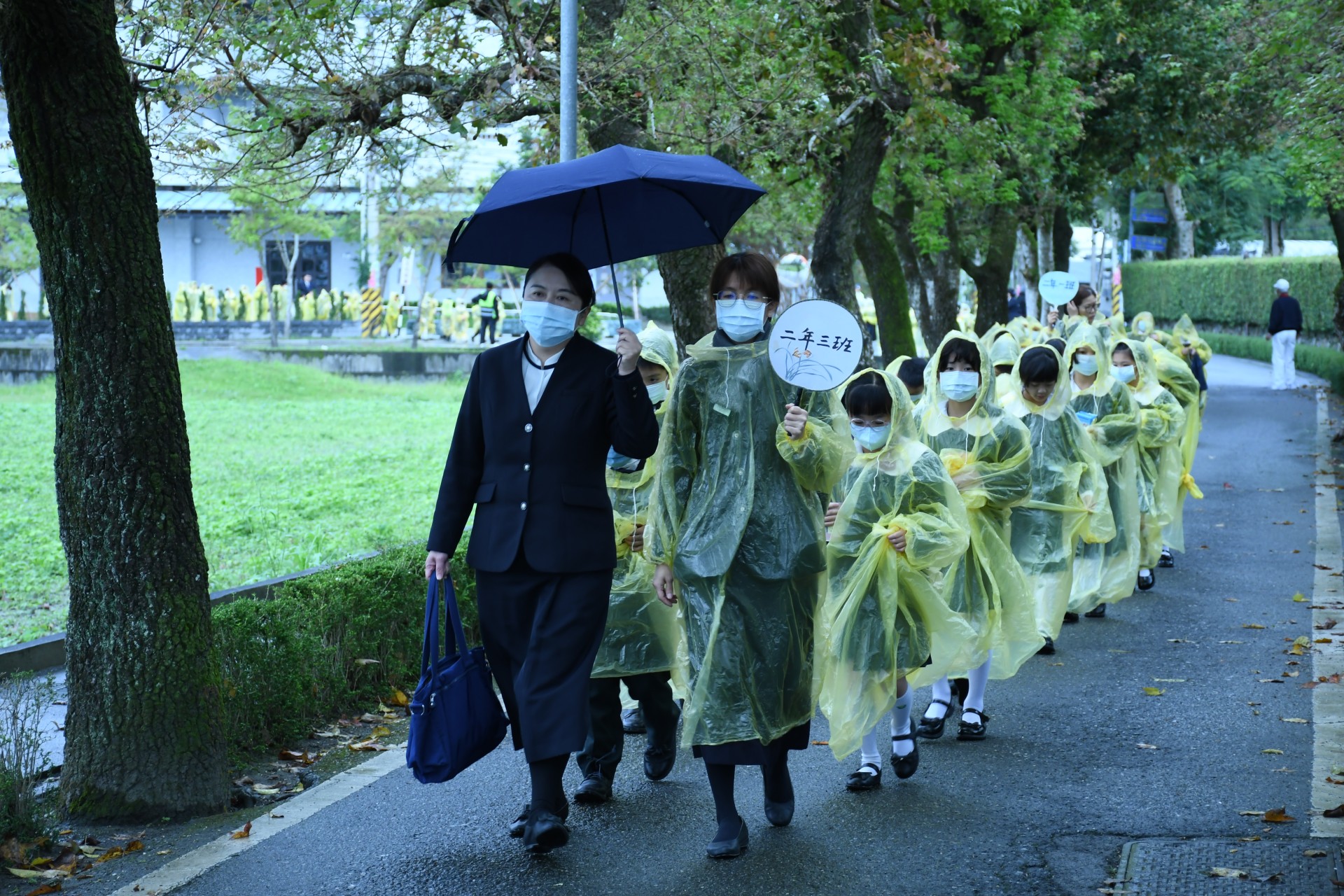 細雨中，慈大附中廖逸貞校長帶領師生走回靜思精舍。孩子們穿著雨衣，帶著存滿善款的竹筒親自送回靜思精舍。