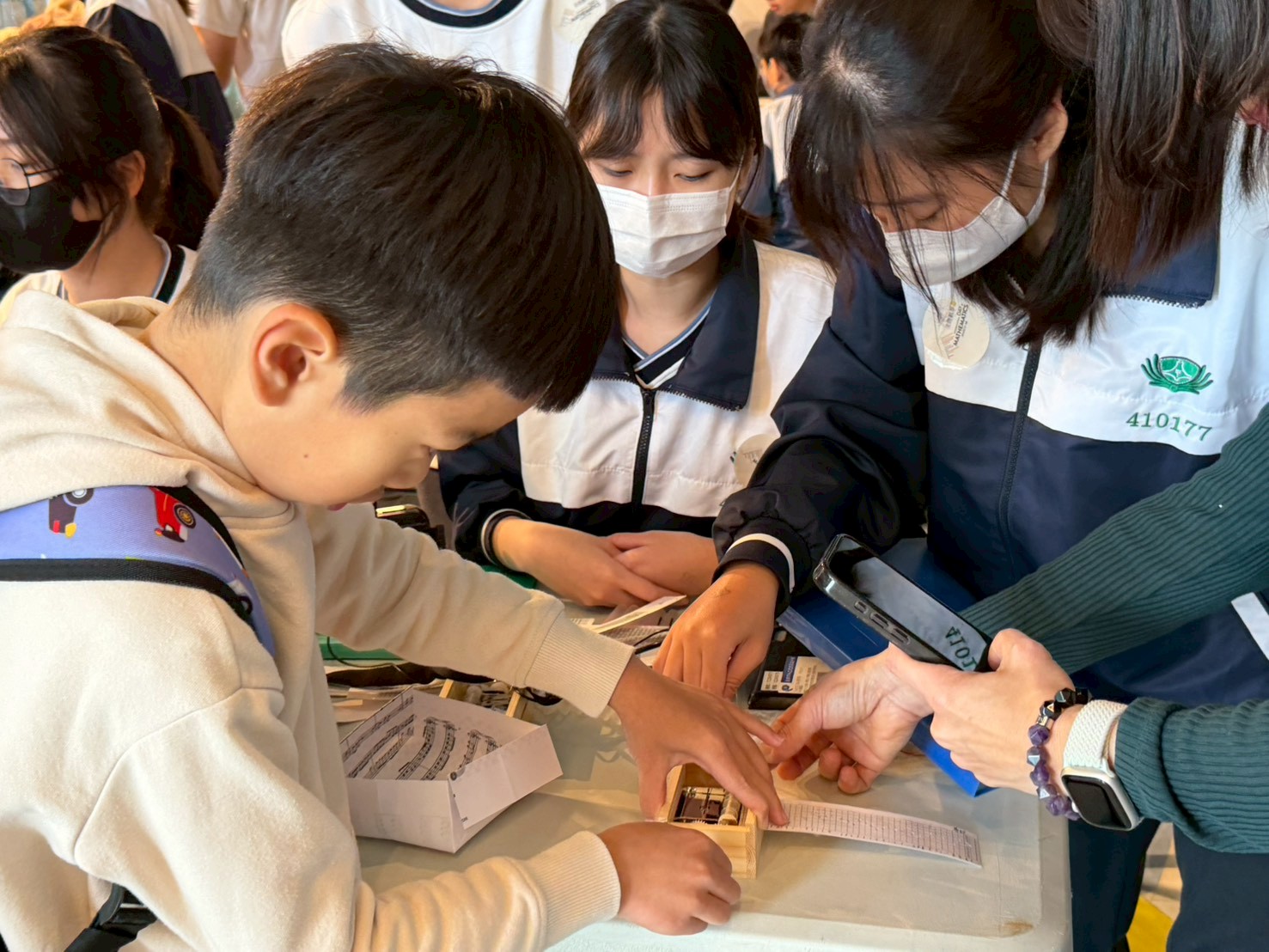 孩子在做好打孔曲譜後,實際將曲譜放入音樂盒內,轉動轉軸,聆聽傳出來的清亮樂聲。