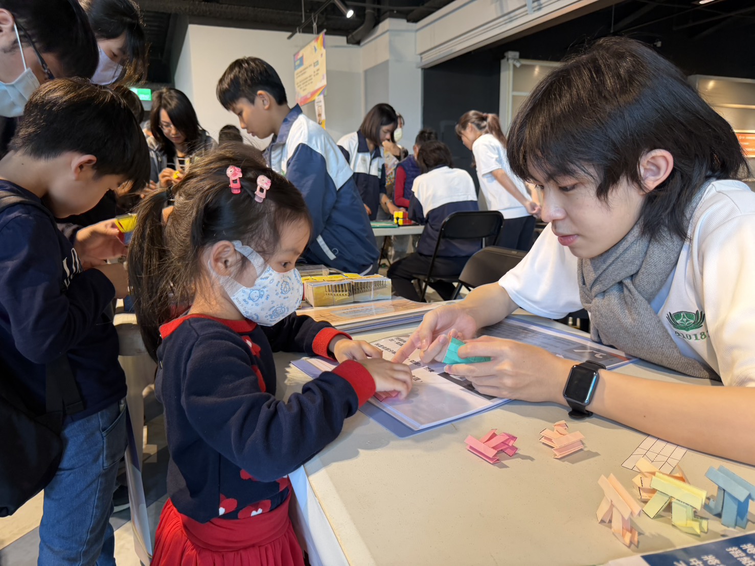 攤位人潮絡繹不絕,學生們透過教具手冊與實際演示,將平面紙張化為立體符號。