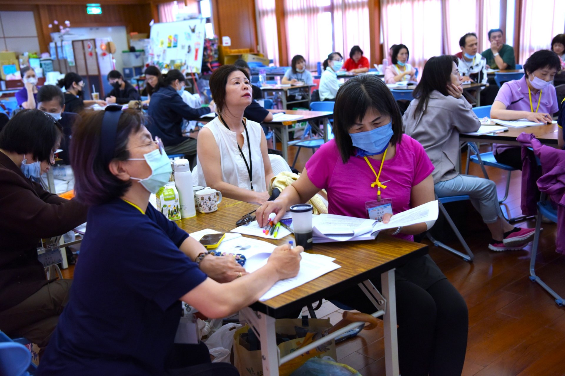測驗涵蓋「學科筆試」與「術科考試」，甚至包含「臨場模擬」環節，模擬學員在面對真實社區長者時的指導情境與應變能力，學員勤作筆記。