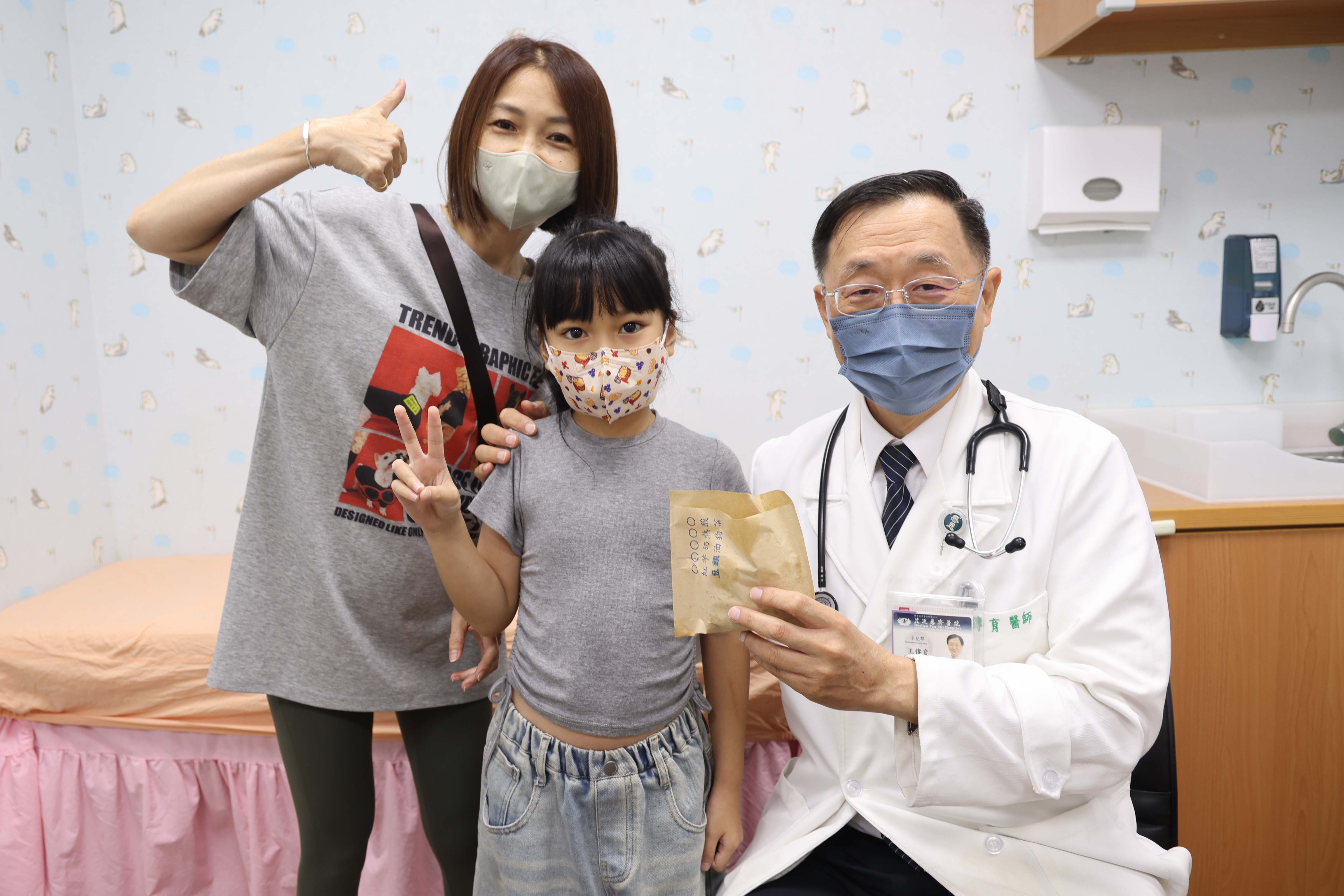 黃小妹(中)回診時，特別送上她最喜歡的點心甜甜圈，感謝兒童神經科主任王傳育(右)。
