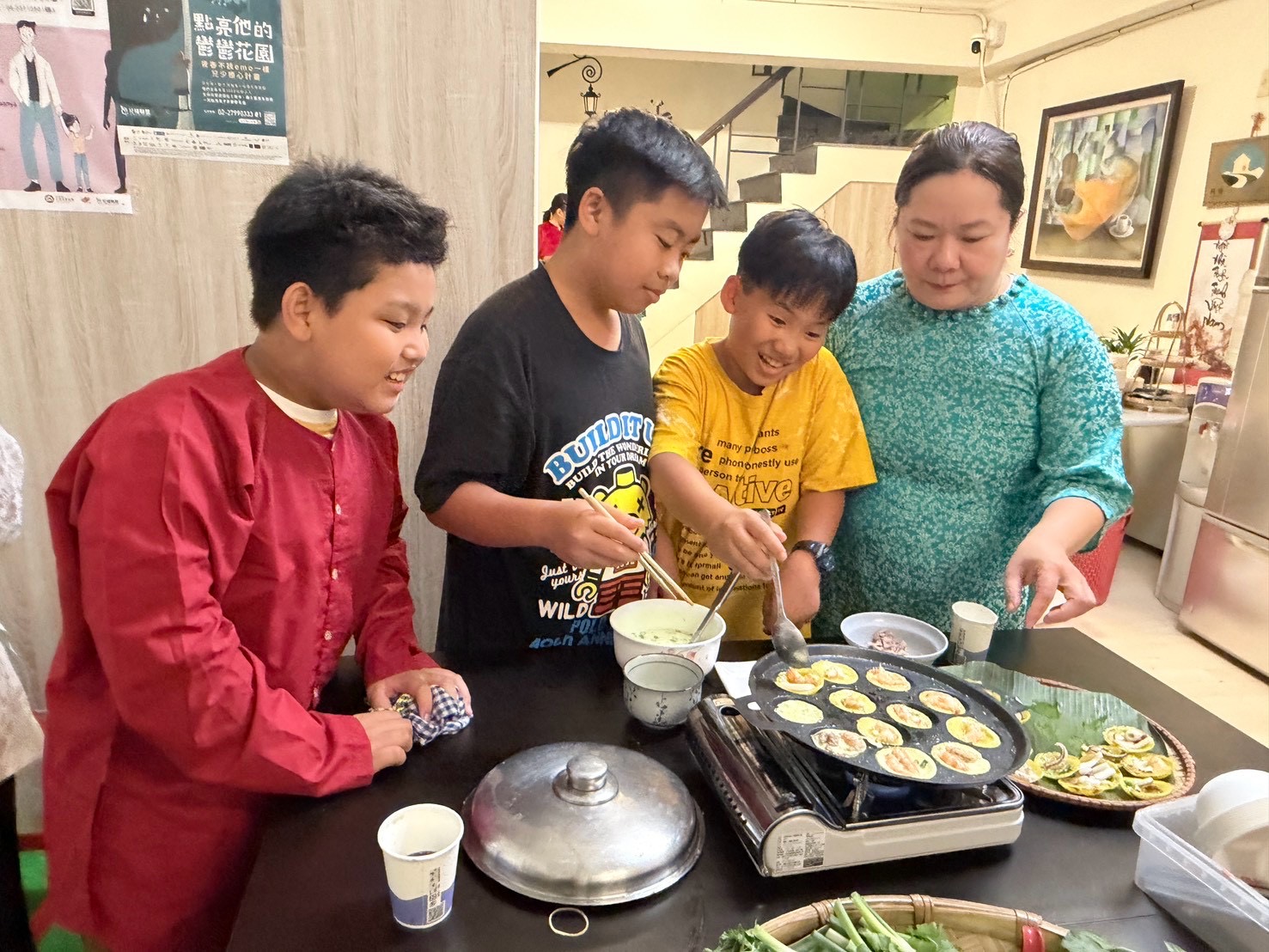 活動現場充滿歡樂的親子互動氣氛,孩子們興奮圍聚在爐邊體驗越南特色煎餅的烹調過程,共享溫馨且寓教於樂的多元文化時光。