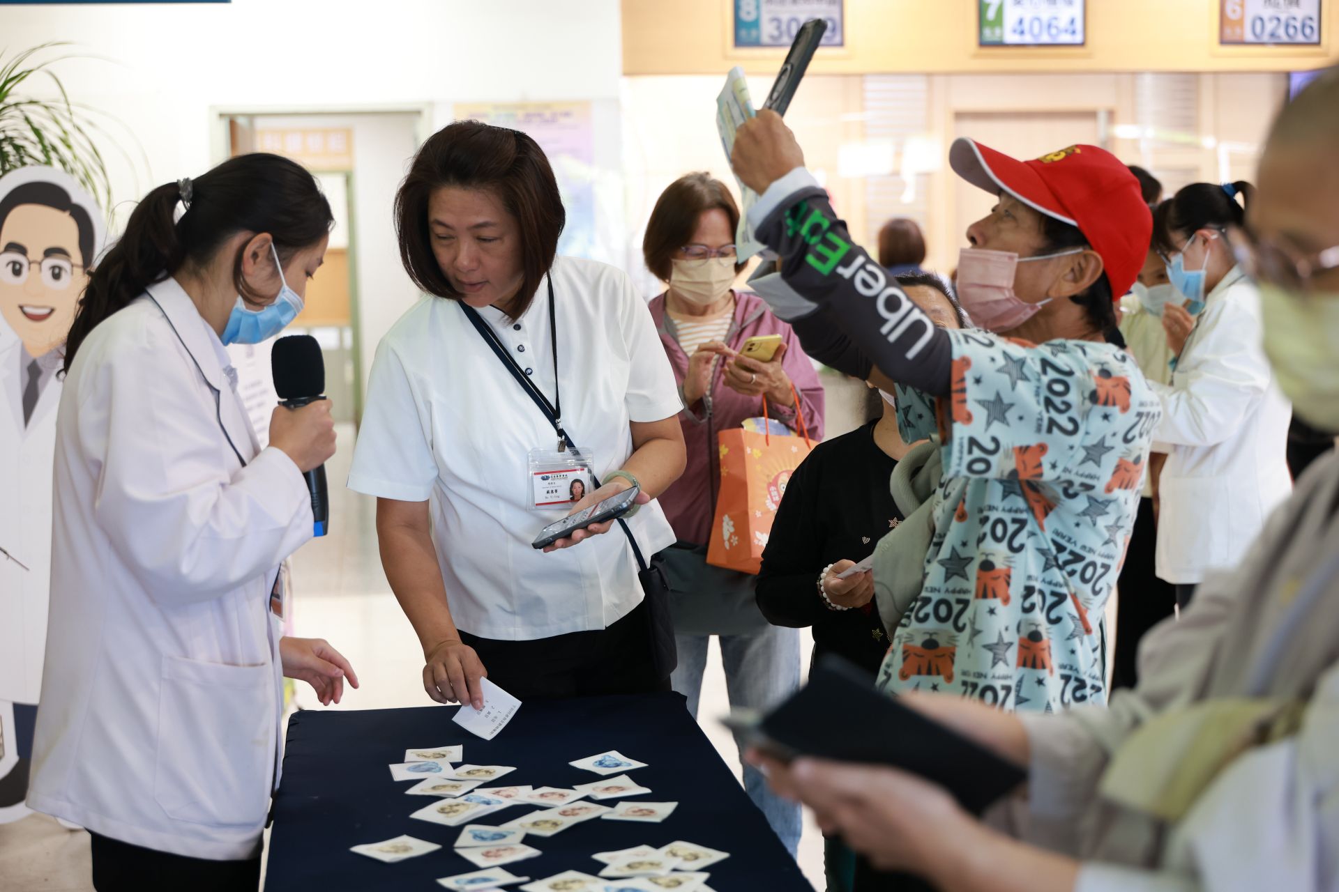 營養科謝淳雅營養師與門診大聽民眾，透過衛教有獎徵答，兌換毛豆豆漿卡士達蛋糕。